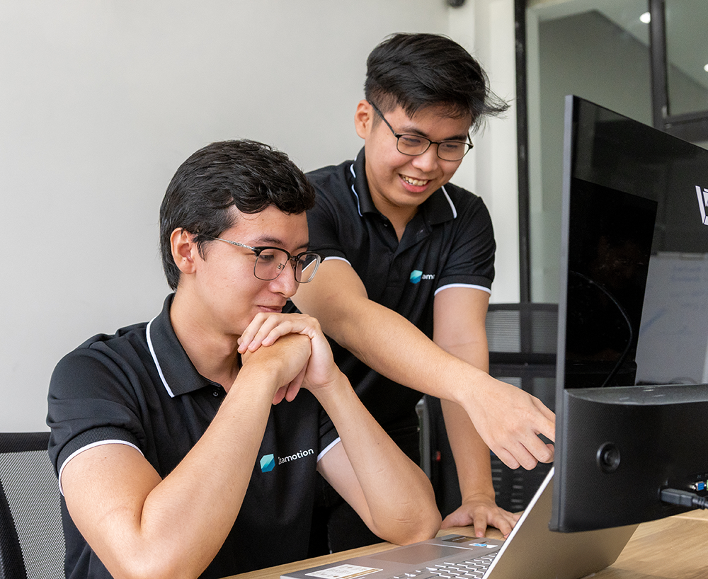 Two Zetamotion engineers collaborating on a laptop during AI-powered quality control project development.